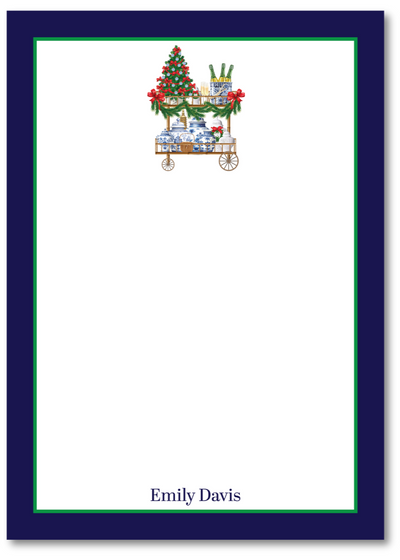 Note card with a Christmas-themed design of a cart with a tree and presents, on a white background with a blue border.